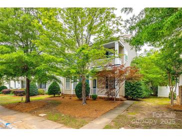 Charming two-story home with a covered porch and balcony, surrounded by mature trees and landscaping at 10407 Alvarado Way, Charlotte, NC 28277