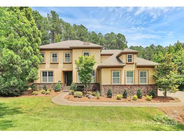 Stunning two-story home with manicured lawn, mature trees, and elegant stone accents under a partly cloudy sky at 11052 Preservation Park Dr, Charlotte, NC 28214