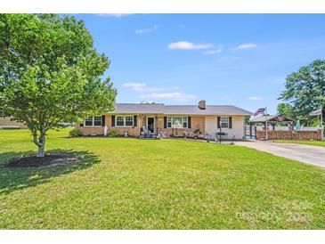 Charming single-story home with a well-maintained lawn, mature tree and American flag at 1204 N 12Th St, Bessemer City, NC 28016