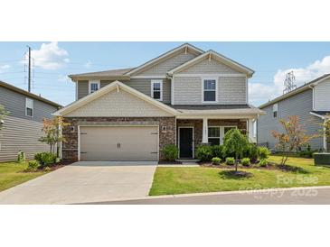 Charming two-story home featuring stone accents, a two-car garage, and well-manicured front yard at 15023 Longmoore Dr, Charlotte, NC 28278