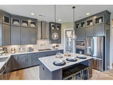 Modern kitchen features gray cabinets, stainless steel appliances, a spacious island and stylish pendant lighting at 18145 Sulton Ter, Huntersville, NC 28078