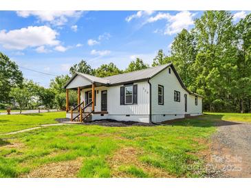 Charming exterior view of home showcasing the metal roof and manicured yard with mature trees at 320 E Pine St, Maiden, NC 28650