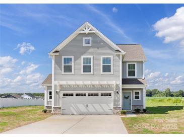 Charming two-story home with gray siding, a two car garage, and a well-manicured lawn at 32562-B Millingport Rd # 7155, New London, NC 28127