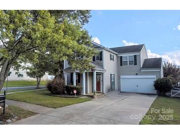Charming two-story home with a well-manicured lawn, gray siding, and a driveway leading to an attached garage at 6107 Raisin Tree Ln, Charlotte, NC 28215