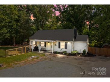 Inviting home exterior featuring a cozy porch swing, landscaped yard, and outdoor lighting for evening ambiance at 800 Woodlawn St, Belmont, NC 28012