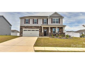 Charming two-story home featuring a two-car garage, stone accents, and a well-manicured front yard at 9505 Cotswood Pl, Gastonia, NC 28056
