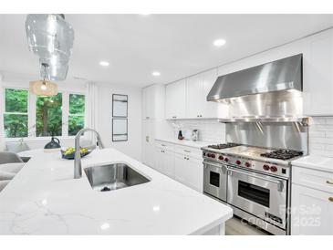 Bright kitchen with quartz countertops, white cabinets, stainless steel appliances, and stylish pendant lighting at 9826 Meringue Pl # 15, Charlotte, NC 28270