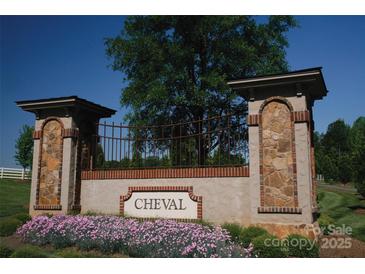 A welcoming Cheval community entrance with stone pillars, iron gate, and colorful flower beds at 3728 Piaffe Ave, Mint Hill, NC 28227