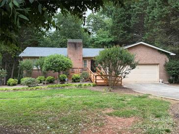 Charming brick home featuring a manicured lawn, a chimney, and a wooden deck at 5198 Wright Dr, Hickory, NC 28602