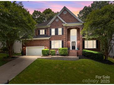 Beautiful two-story brick home with a well-manicured lawn, mature trees, and an attached two-car garage at 11909 Cupworth Ct, Huntersville, NC 28078