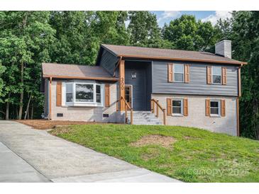 Charming home featuring horizontal siding, brick foundation, wooden shutters, and manicured lawn at 300 Dollar Cir, Charlotte, NC 28270