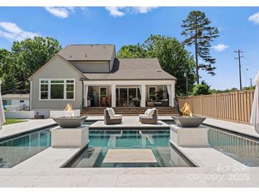 Resort style backyard with luxurious pool and fire bowls plus covered patio seating area at 4021 Redwood Ave, Charlotte, NC 28205