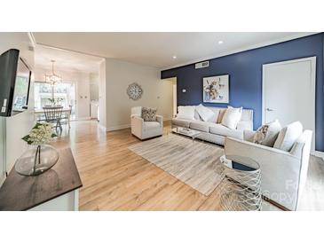 Bright living room with a striking blue accent wall, plush seating and light wood flooring at 5927 Quail Hollow Rd # H, Charlotte, NC 28210