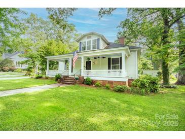 Charming home featuring a spacious front porch, lush green lawn, and mature trees offering shade at 636 N Center St, Statesville, NC 28677