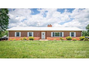 Charming brick ranch home featuring a white roof, tidy lawn, and well-maintained landscaping at 765 York Institute Rd, Hiddenite, NC 28636