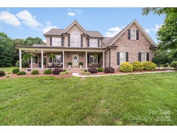 Charming brick home featuring a covered front porch and lush landscaping at 1533 Ohara Plantation Ct, Dallas, NC 28034