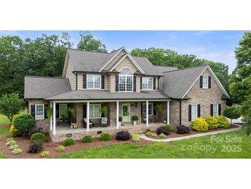 Charming brick home featuring a large front porch with decorative columns and lush landscaping at 1533 Ohara Plantation Ct, Dallas, NC 28034