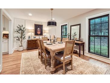 A formal dining room boasts a wooden table, complementing the hardwood floors and natural light at 3214 Tilley Morris Rd, Matthews, NC 28105