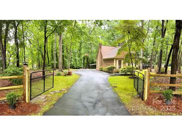 Gated driveway leading to a charming home surrounded by lush greenery at 3214 Tilley Morris Rd, Matthews, NC 28105