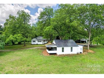 Aerial view of a quaint white home with mature trees on a lush green lawn at 615 & 625 Irish Potato Rd, Concord, NC 28025