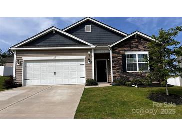 Charming single-story home showcasing a stone facade, two-car garage and well-manicured lawn at 640 Yellow Birch Dr, Locust, NC 28097
