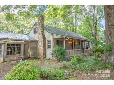 Charming home featuring a stone chimney, covered porch, and lush greenery at 749 N Miller Ave, Statesville, NC 28677