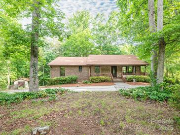 Charming brick home nestled among mature trees, boasting a covered front porch and lush landscaping at 9300 Surrey Rd, Mint Hill, NC 28227