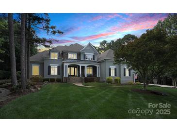 Elegant home with manicured lawn, stone accents, covered porch and stunning evening sky backdrop at 167 Quaker Rd, Mooresville, NC 28117