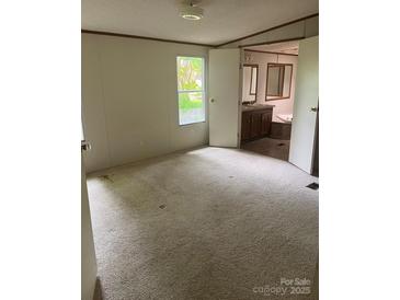 Bright bedroom featuring neutral carpet, a window and open doorway to the en-suite bathroom at 4006 Hillview Dr, Shelby, NC 28152