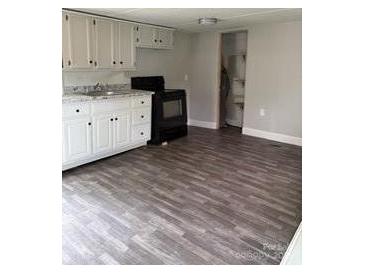 A cozy kitchen features white cabinets, laminate counter tops, and wood grain vinyl floors at 4417 Grier St, Gastonia, NC 28056