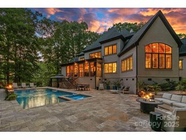 Luxury backyard features a pool, spa, and an outdoor seating area perfect for entertaining under a colorful sunset sky at 10300 Sweetleaf Pl, Charlotte, NC 28278
