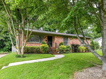 Charming brick home featuring a well-manicured lawn and lush landscaping at 1638 Wensley Dr, Charlotte, NC 28210