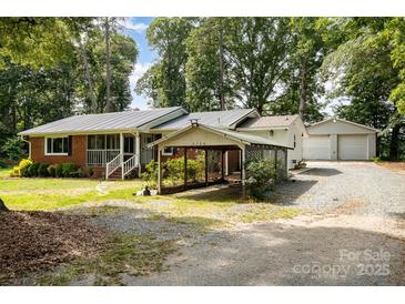 Charming brick home featuring a carport and detached garage, nestled amidst lush greenery and a spacious front yard at 2320 Doster Rd, Monroe, NC 28112