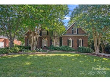 Charming brick home with lush landscaping and mature trees in a well-maintained front yard at 3506 Cardiff Ln, Matthews, NC 28104