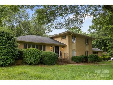 Traditional two-story brick home featuring mature trees, manicured shrubs and well-maintained lawn at 6017 Sierra Dr, Charlotte, NC 28216