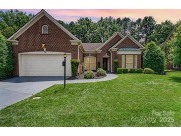 Charming brick home with manicured lawn and landscaping, plus a two-car garage and inviting walkway at 7211 Baniff Cir, Charlotte, NC 28277
