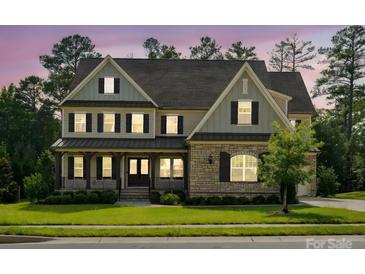 Charming two-story home featuring a stone facade, covered porch, and manicured lawn at 1008 Ladera Dr, Waxhaw, NC 28173