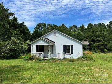 Quaint one-story white home with a covered porch, nestled amongst mature trees and lush landscaping at 2791 Neill Rd, Lancaster, SC 29720