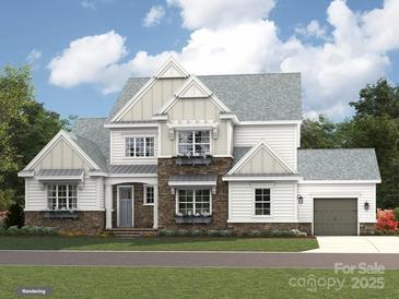 New construction boasts a modern farmhouse elevation with stone accents and a welcoming two-car garage at 1001 Kingbird Ln # 15, Clover, SC 29710