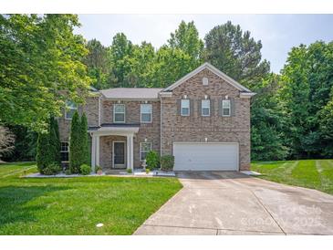 Charming two-story brick home with an attached two-car garage, manicured lawn, and lush landscaping at 10044 Markus Dr, Mint Hill, NC 28227