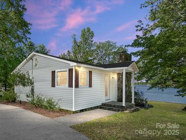 Charming single-story home with stone chimney, brown shutters, and lake views at sunset at 17835 Terryglass Ln, Charlotte, NC 28278