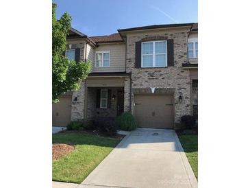 Charming brick and siding townhome features a one car garage and well-maintained front yard at 9593 Camberley Nw Ave, Concord, NC 28027