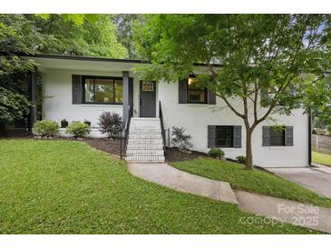 Charming white brick home with black accents and a welcoming front yard with mature tree at 1021 Nancy Dr, Charlotte, NC 28211