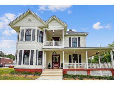 Charming two-story home showcasing a welcoming front porch, accented by red trim and black window shutters at 107 Hinton St, Chester, SC 29706