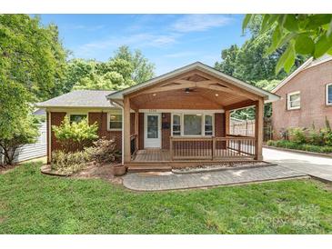 Charming brick home featuring a welcoming wooden front porch with a cozy seating area at 1734 Seifert Cir, Charlotte, NC 28205