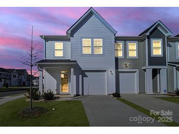 Charming townhome with neutral siding, attached garage, and well-manicured lawn at dusk at 240 Briana Marie Way, Indian Trail, NC 28079