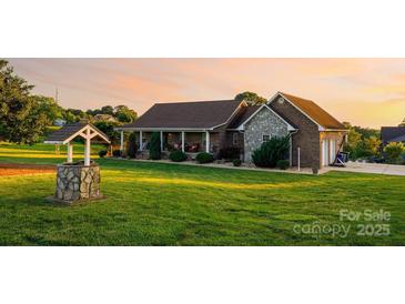 Beautiful brick home featuring a well, lush lawn, and a charming covered front porch at sunset at 2843 Startown Rd, Lincolnton, NC 28092