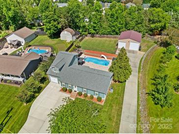Expansive aerial view of a home with a pool, detached garage, green lawn and mature trees at 2908 Dylan Nw Pl, Concord, NC 28027