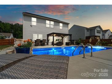 Inviting backyard oasis features a sparkling pool, lounge chairs, and pergola seating, perfect for relaxing and entertaining at 3092 Riker St, Clover, SC 29710