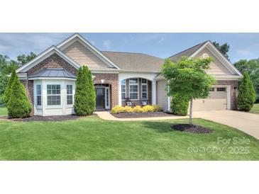Charming brick and siding home with manicured front lawn, mature trees, and inviting front entrance at 317 Annatto Way, Tega Cay, SC 29708